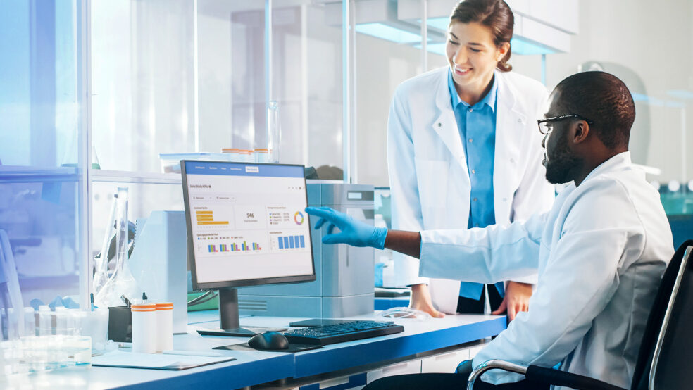 two clinical researchers interacting with data on a computer screen
